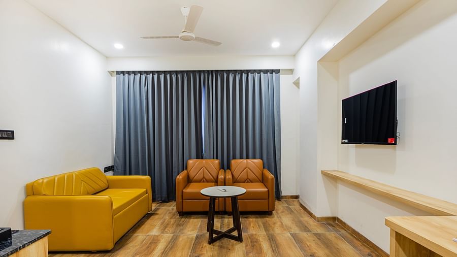 Lemonridge Hotels, KPHB | Hotel room with a sofa, two armchairs, and a coffee table.  TV on the wall. Comfortable seating area.